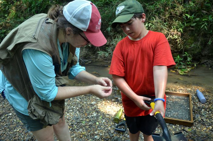 Museum education outreach coordinator Allie Sorlie shows Jacob Hutson, 9, a fossilized shark tooth.